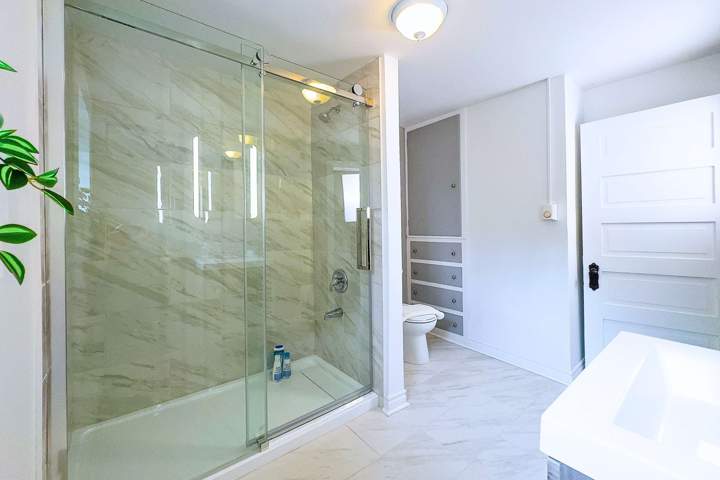 A modern bathroom with a glass shower enclosure, a white toilet, and a white sink.