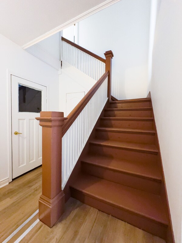 Een houten trap met witte leuningen en een deur aan de bovenkant.