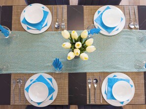 A dining table set with plates, cutlery, and a centerpiece of white flowers.
