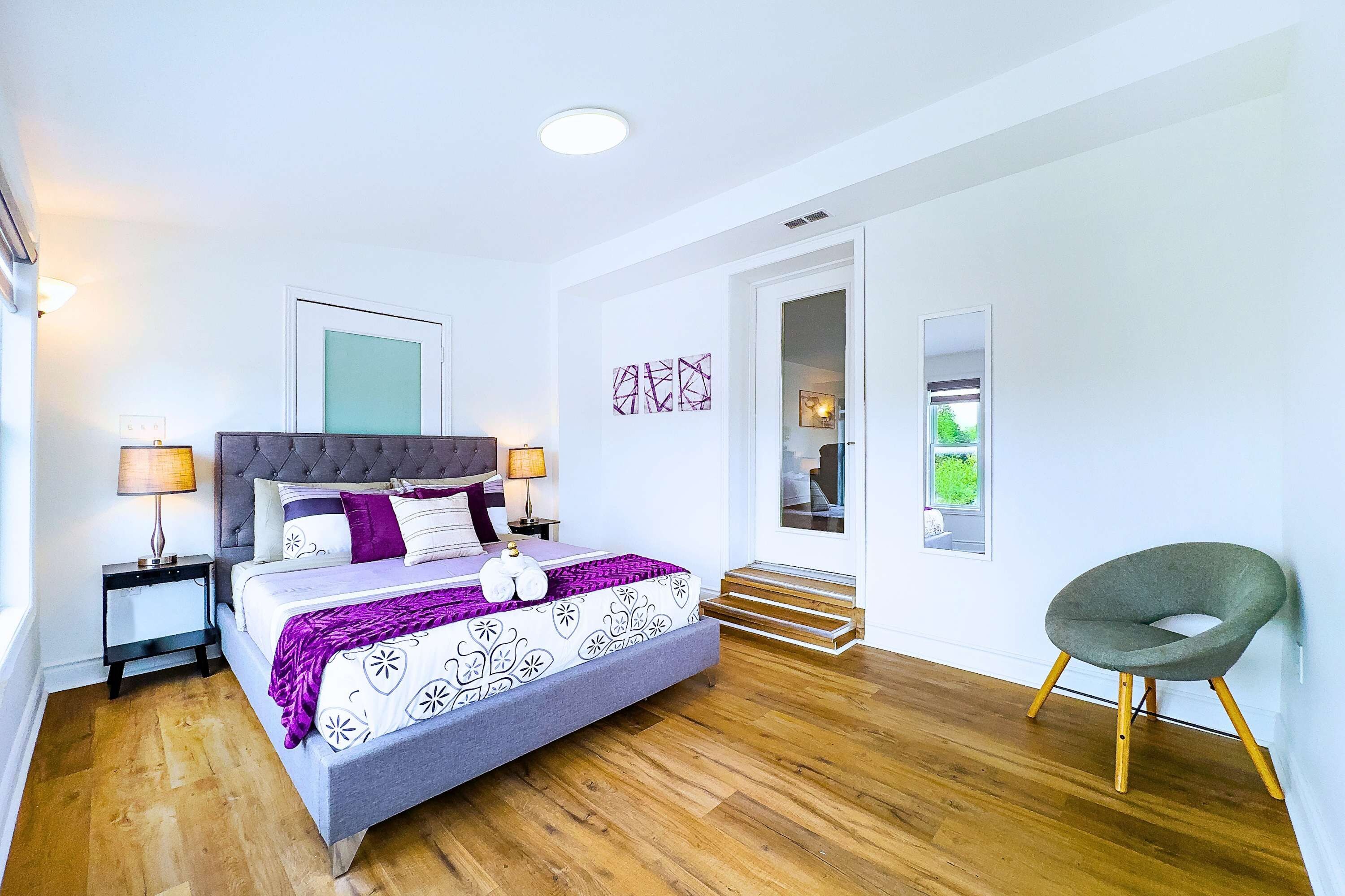 A bedroom with a bed, bedside tables, a chair, a door, and a window.
