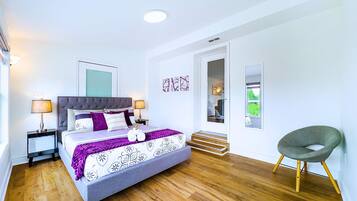 A bedroom with a bed, bedside tables, a chair, a door, and a window.