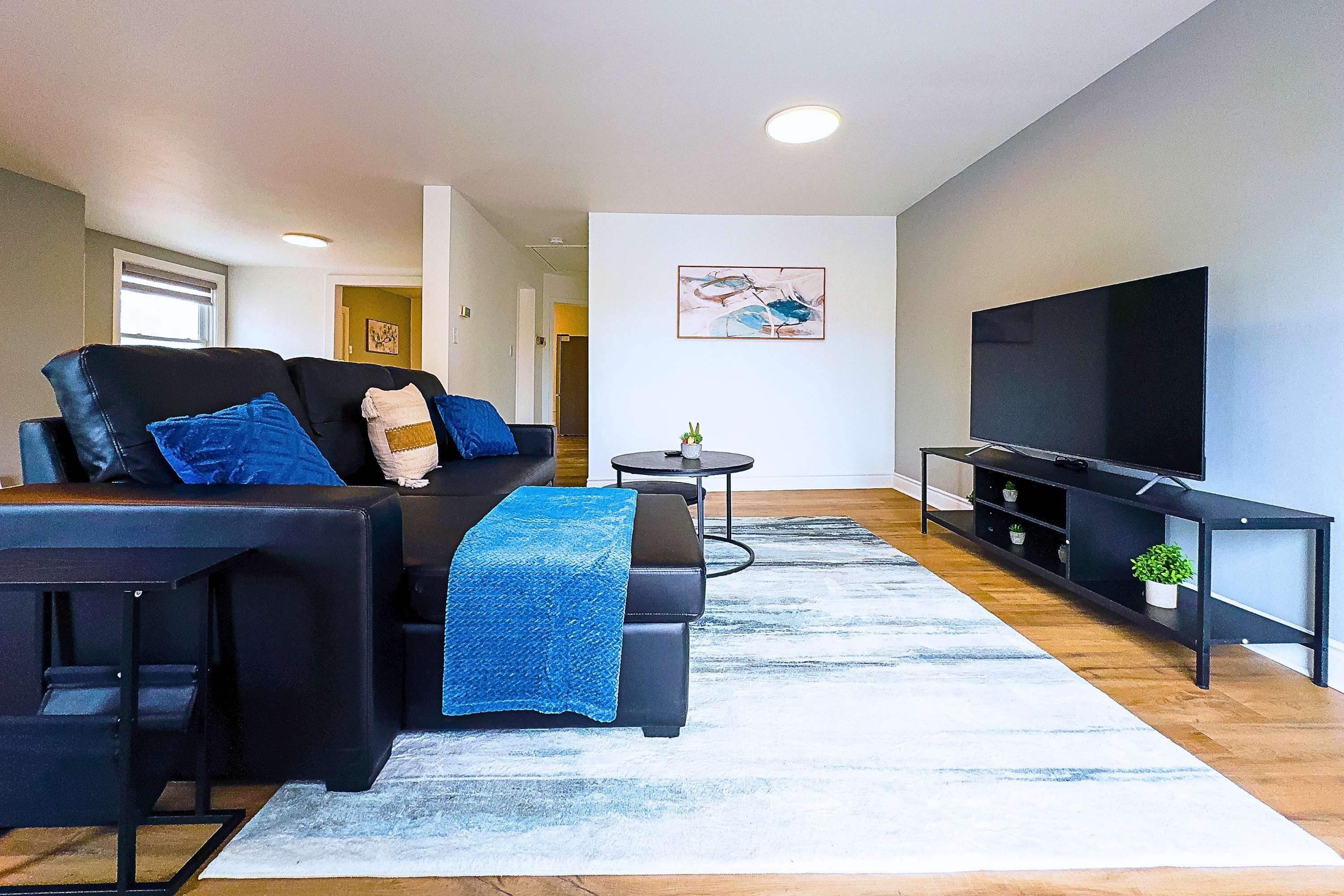 A modern living room with a sofa, coffee table, TV, and artwork on the wall.