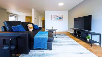 A modern living room with a sofa, coffee table, TV, and artwork on the wall.