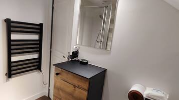 A modern bathroom with a wooden vanity, a black towel rack, a mirror, and a toilet paper holder.