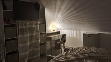 Une chambre à coucher faiblement éclairée, avec un lit, un bureau et une chaise.