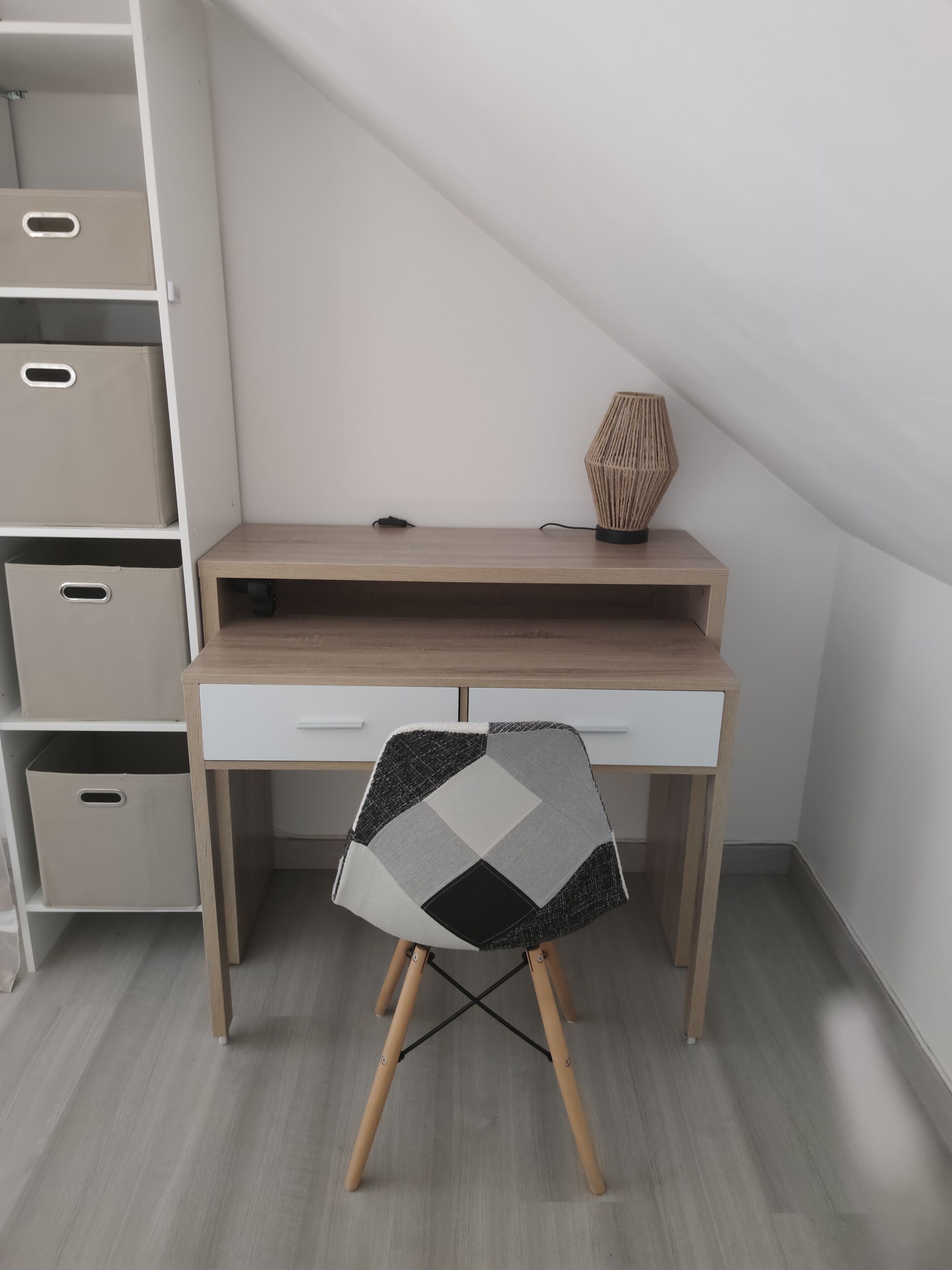 A corner desk with a chair, a lamp, and storage bins.