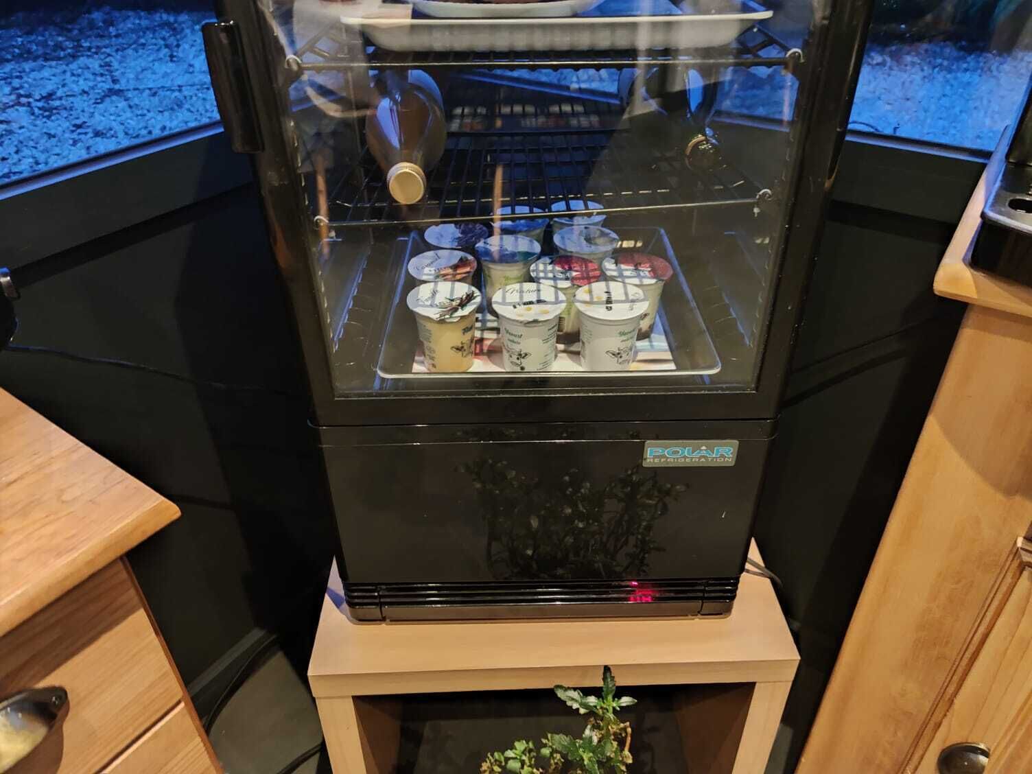 Une machine à café dotée d’une enceinte en verre, dans laquelle on peut voir plusieurs tasses de café.