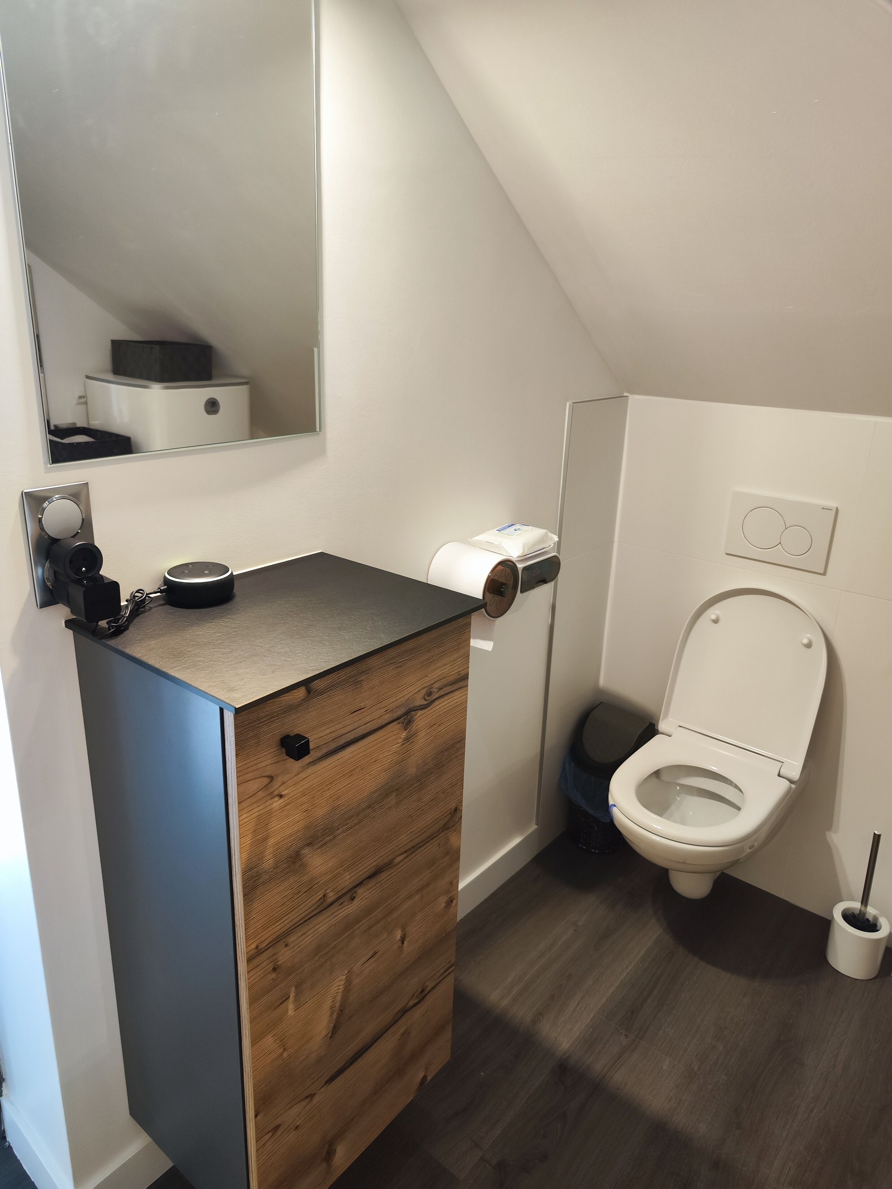 Une salle de bain moderne avec un meuble-lavabo en bois, des toilettes et un miroir.