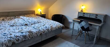 Un dormitorio con cama, escritorio, silla y tragaluz.