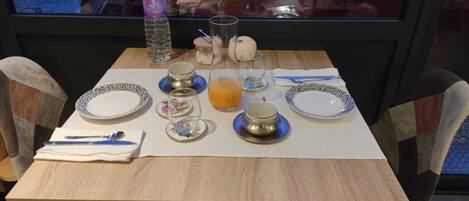 Una mesa de comedor dispuesta con platos, vasos, una botella de agua y un vaso de jugo de naranja.