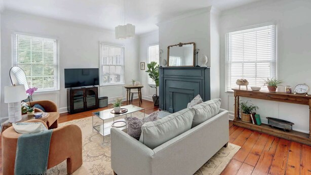 A living room with a sofa, TV, fireplace, and a dining area with a table and chairs. - Heritage Loft @ The Murphy House, Chippewa Square! (Savannah)