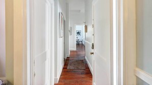 A hallway with white walls, wooden flooring, and a door with a brass handle. - Heritage Loft @ The Murphy House, Chippewa Square! (Savannah)