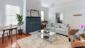 A living room with a fireplace, sofa, coffee table, and potted plants. - Heritage Loft @ The Murphy House, Chippewa Square! (Savannah)