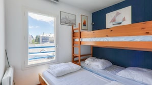 Una habitación con literas, una ventana que da a edificios y cuadros en la pared.