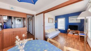 Una habitación con una mesa de comedor, un sofá, un mueble para la TV y un ventilador de techo.