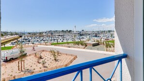 Un puerto deportivo con numerosas embarcaciones amarradas, un camino para peatones y un aparcamiento con una furgoneta.