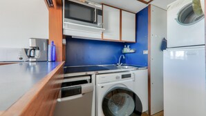 Una kitchenette compacta con microondas, cafetera y lavadora.