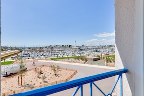 A marina with numerous boats docked, a pedestrian pathway, and a parking area with a van.
