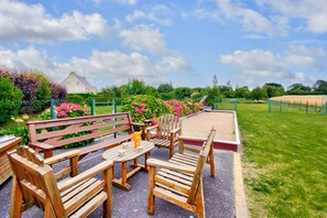 Relax in a serene outdoor space surrounded by lush greenery and vibrant flowers, with comfortable seating and tables.