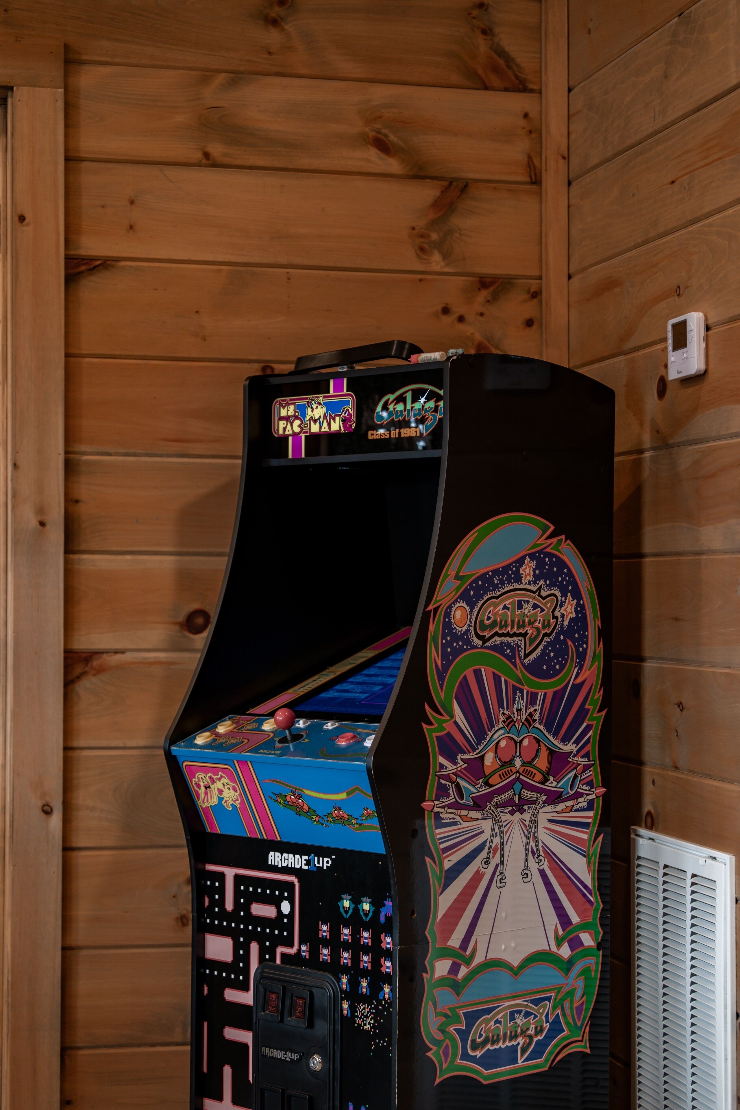 A vintage arcade machine with a colorful design, mounted on a wooden wall.