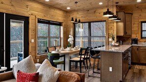 A cozy cabin-style kitchen with wooden walls, a dining area with a table and chairs, and a built-in island with a coffee maker.