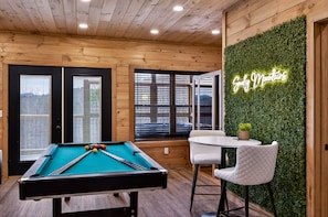 A pool table with a neon sign, wooden walls, and a green wall with a plant. - Jerne Of A Lifetime 4 Bedroom Cabin by RedAwning (Sevierville)