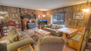 Una sala de estar acogedora con chimenea, televisor, sofá, una mesa de centro y una estantería.