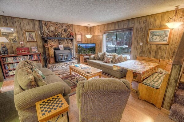 A cozy living room with a fireplace, a television, a sofa, a coffee table, and a bookshelf.