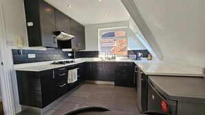 A modern kitchen with dark cabinetry, a gas stove, and a dishwasher. - Apartment - Sleeps 4 & Free Parking (London)