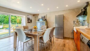 A modern kitchen with a dining area, large windows, and a view of the outdoors. - Longère Charmante et Confortable, Proche de la Pointe Saint Mathieu (Plougonvelin)