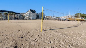 A beach volleyball court with a net, palm trees, and buildings in the background. - Longère Charmante et Confortable, Proche de la Pointe Saint Mathieu (Plougonvelin)