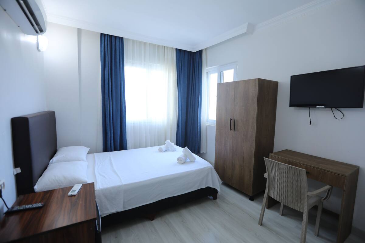 Une chambre d’hôtel équipée d’un lit, d’un bureau, d’une chaise, d’une télévision et d’une armoire.