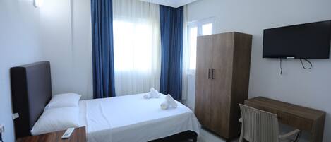 Habitación de hotel con cama, escritorio, silla, televisor y armario.