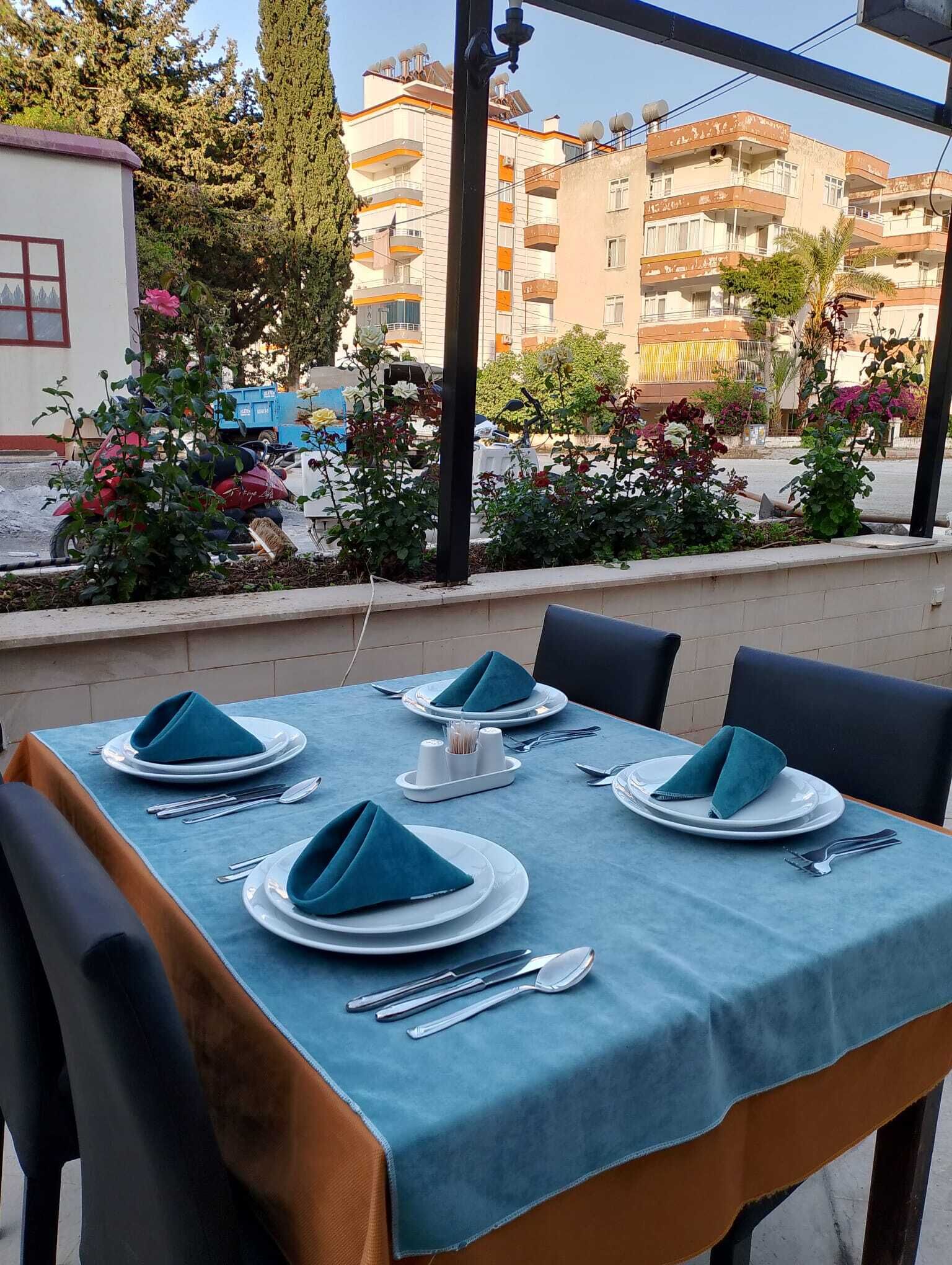 A table set for four with a teal tablecloth, plates, and folded napkins.