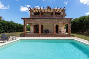 Un edificio de ladrillo de dos plantas con una piscina en frente.