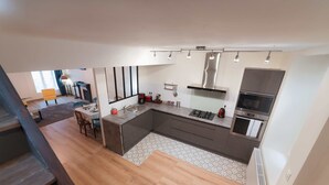 A modern kitchen with a central island, built-in appliances, and a dining area with a table and chairs. - Charming townhouse with a covered and furnished interior patio (Tournus)