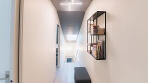 A narrow hallway with a ceiling light fixture, a bench, and a bookshelf on the right wall. - Charming townhouse with a covered and furnished interior patio (Tournus)