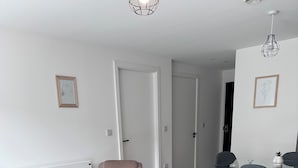 Una sala de estar moderna con sofá, mesa de centro, una silla y un comedor con mesa y sillas.