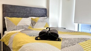 Una cama bien hecha con ropa de cama estampada y una bolsa negra encima.