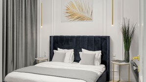 A modern bedroom with a large bed, a chandelier, and a decorative wall piece.