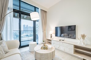 Un salon moderne doté d’une grande fenêtre, d’un téléviseur à écran plat, d’une table basse ronde et d’une console au design minimaliste.