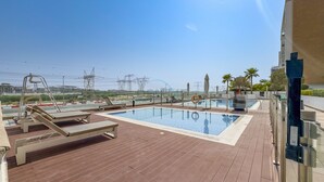 Ein Pool auf dem Dach mit Liegestühlen und Blick auf die Stadt.