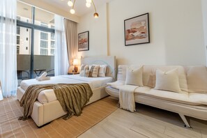 Ett hotellrum med en säng, en soffa, ett skrivbord och en stol. Det hänger två tavlor på väggen.