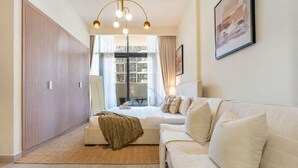 Ein modernes Schlafzimmer mit einer Couch, einem Bett, einem Kleiderschrank und einem großen Fenster.