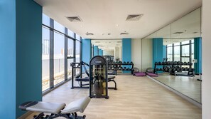 A gym with exercise equipment, mirrors, and large windows.