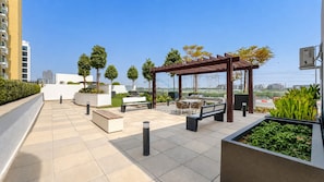 A rooftop terrace with outdoor seating, a pergola, and a view of the cityscape.
