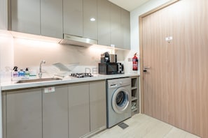 A compact kitchen with a built-in microwave, a sink, and a washing machine.