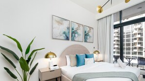 Ein modernes Schlafzimmer mit einem großen Bett, einem Nachttisch, einer Topfpflanze und Bildern an der Wand.
