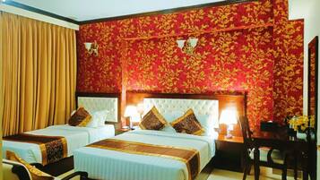 Habitación de hotel con dos camas, papel tapiz floral rojo, una araña y un escritorio con una silla.