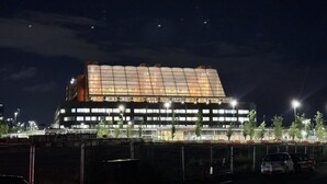 Een groot, modern gebouw met een opvallende, gebogen dakconstructie en veel ramen.